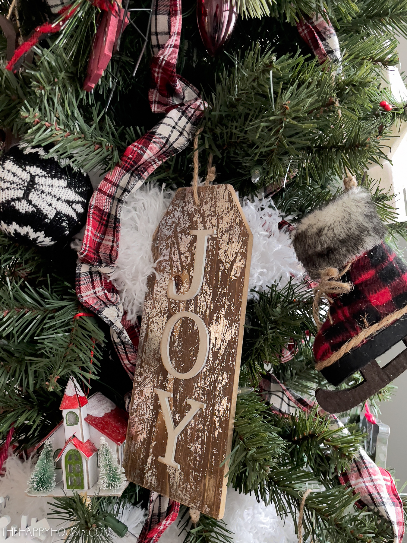 A wooden sign that says Joy on the tree.