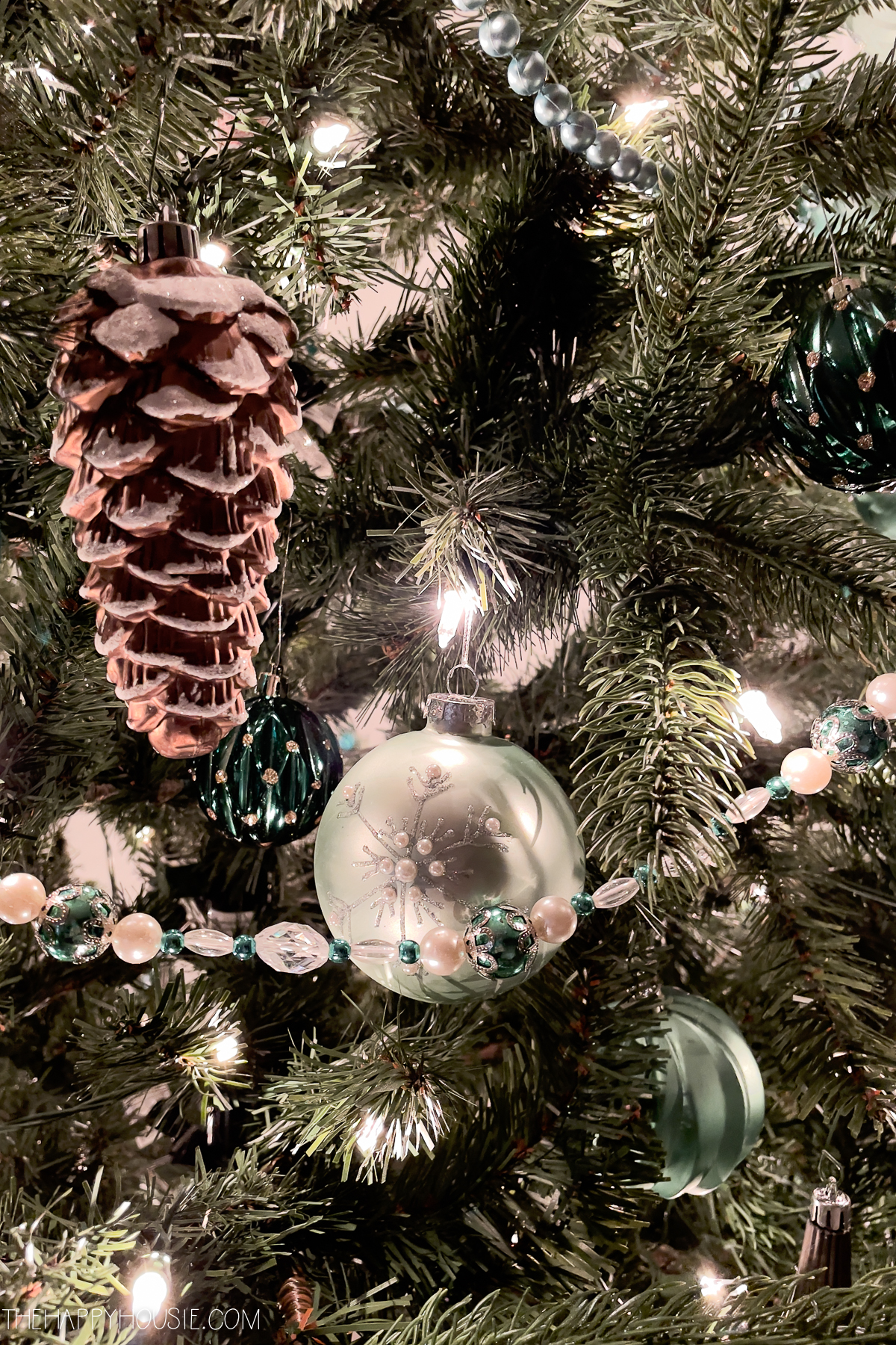 a Christmas tree decorated with green glass balls and glass pine cone ornaments