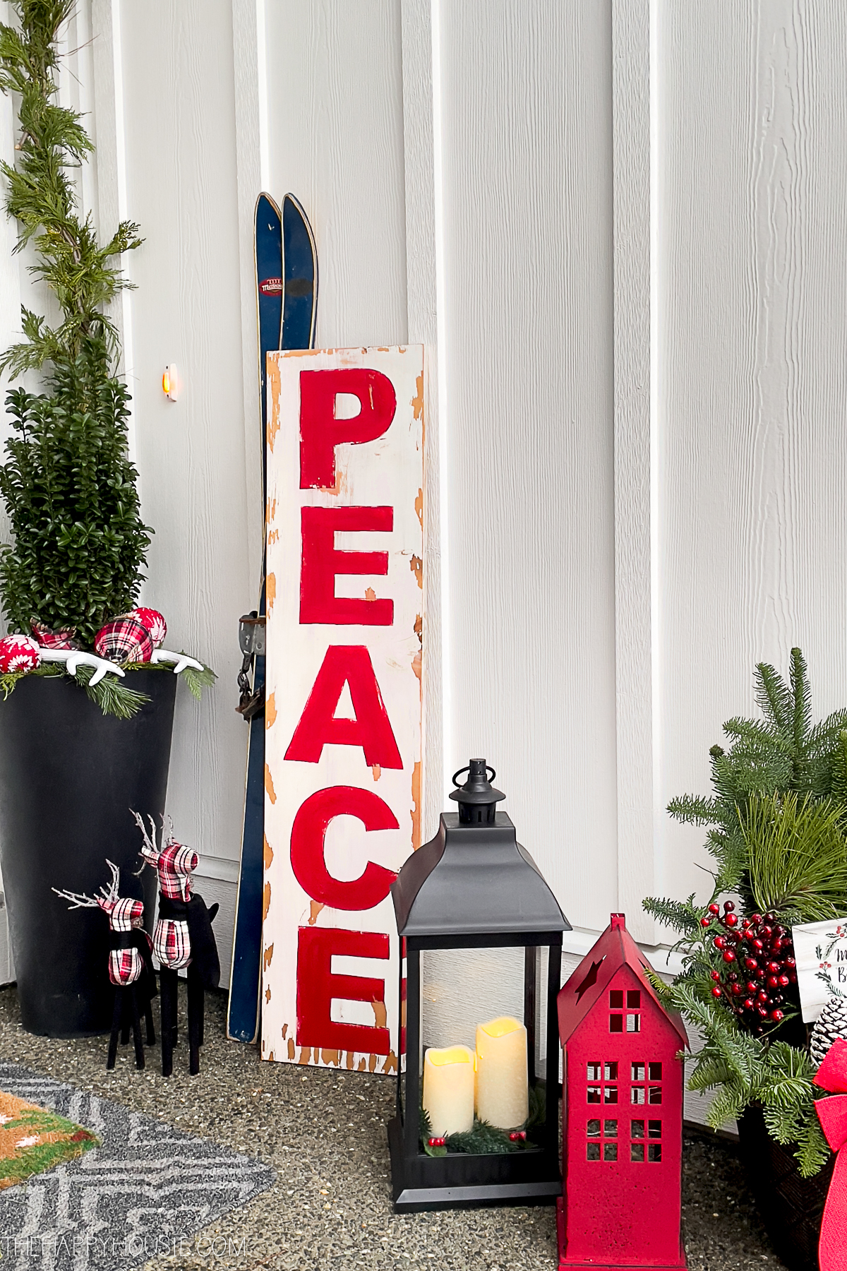 A large wooden PEACE sign displayed on a Christmas porch.