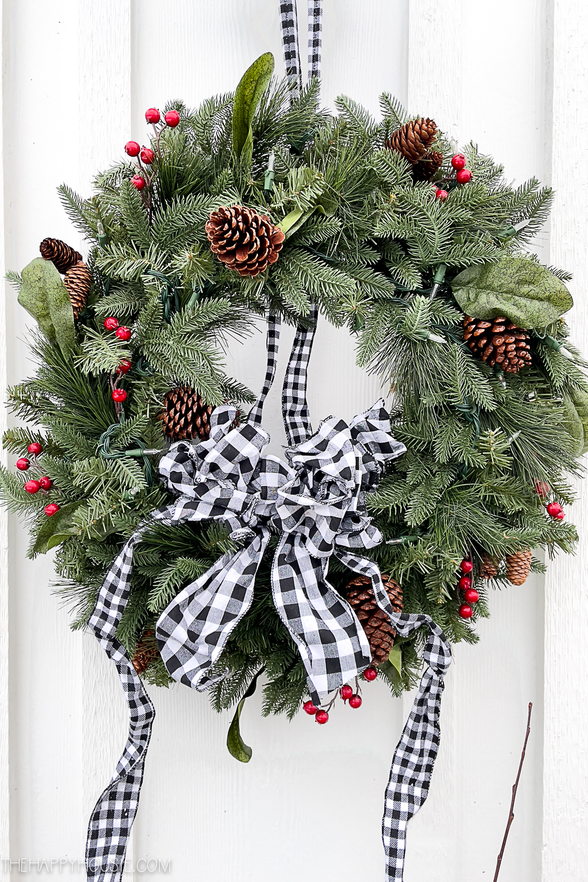a large Christmas wreath dressed up with black and white buffalo check ribbon and bow