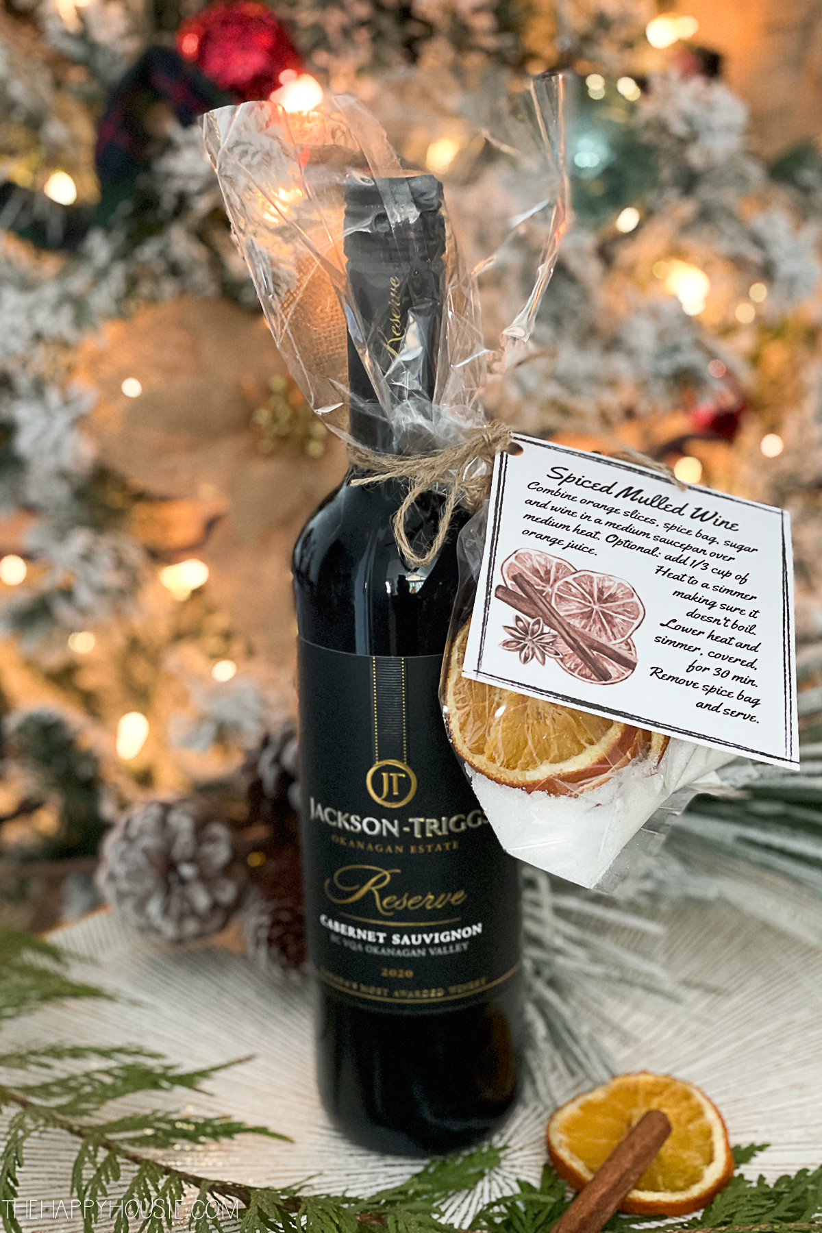 a bottle of red wine with a gift bag of mulling spices attached 