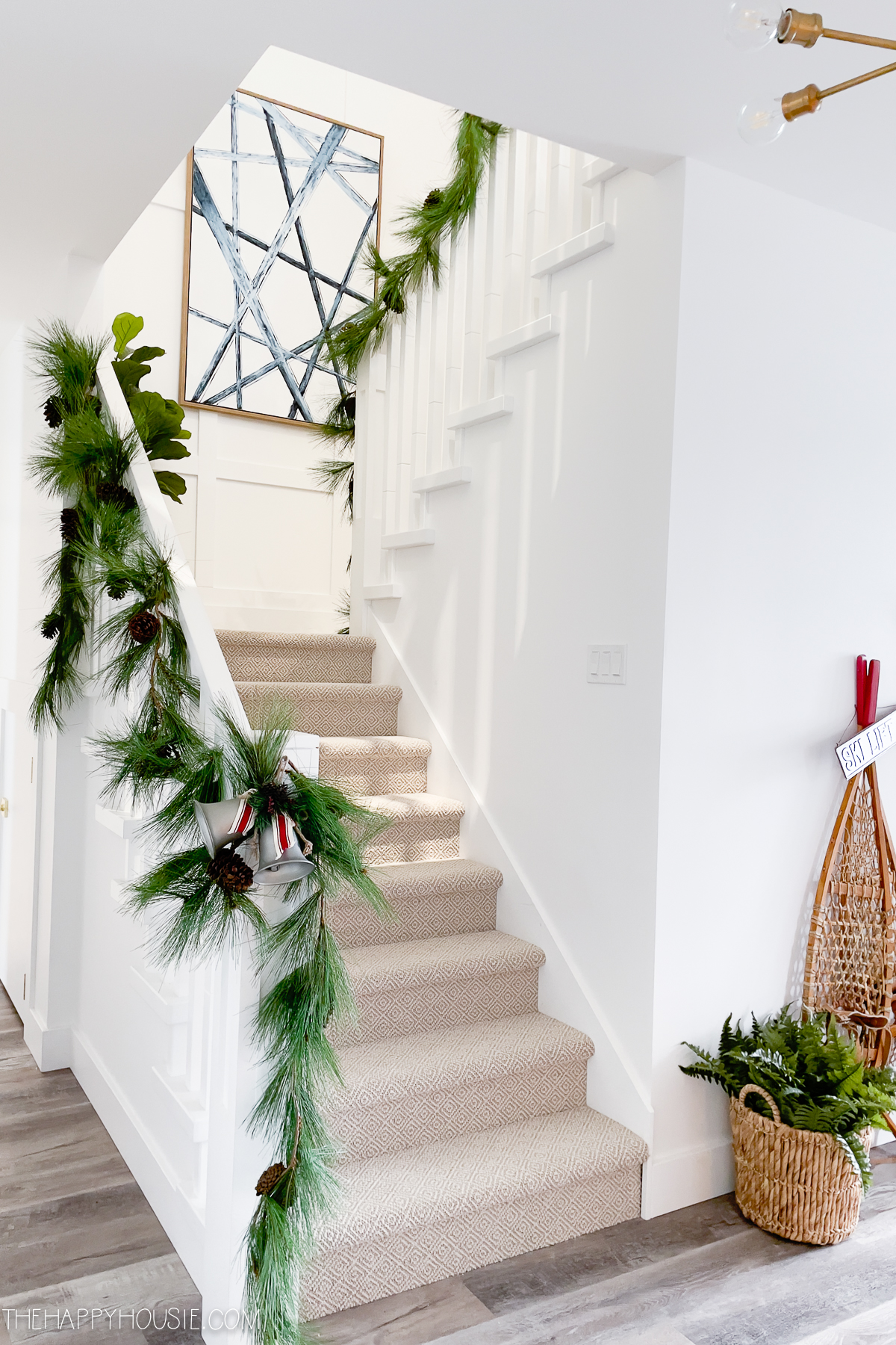 The stairway banister with sprigs of greenery and pine cones.