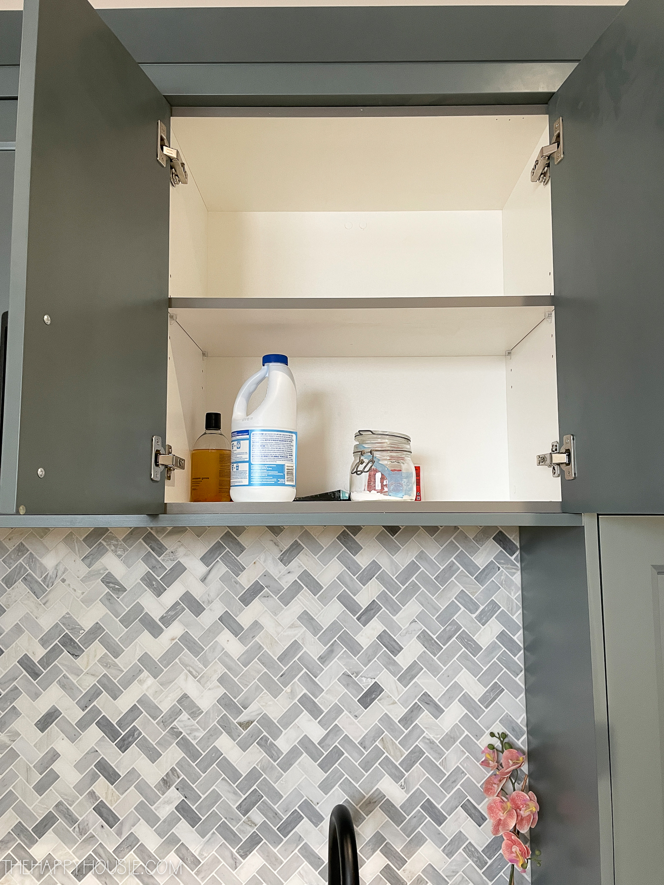 A small cupboard above the sink with a bottle of cleaning supplies.