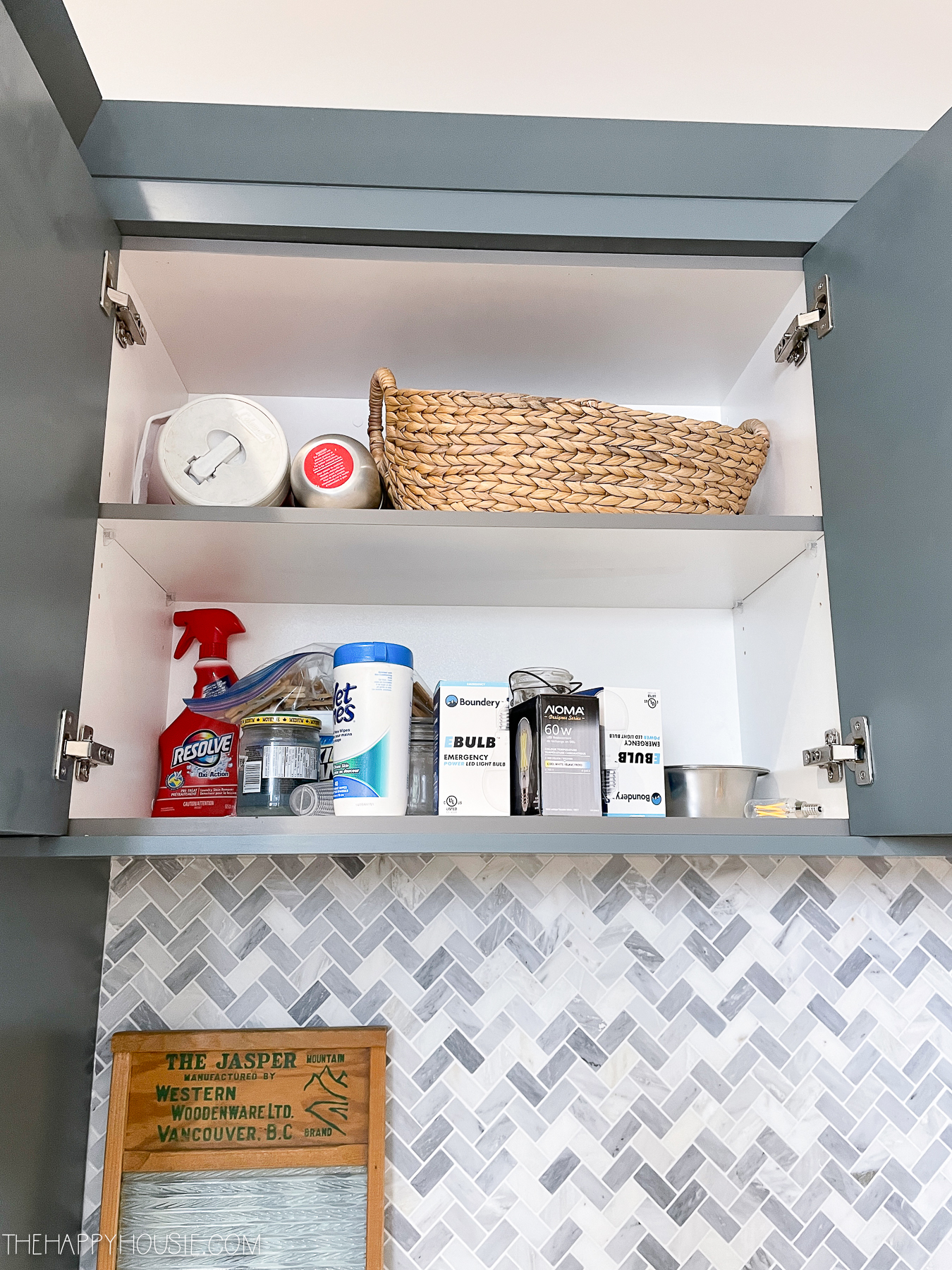 A cupboard in the laundry room above the counter with various cleaning and laundry supplies.