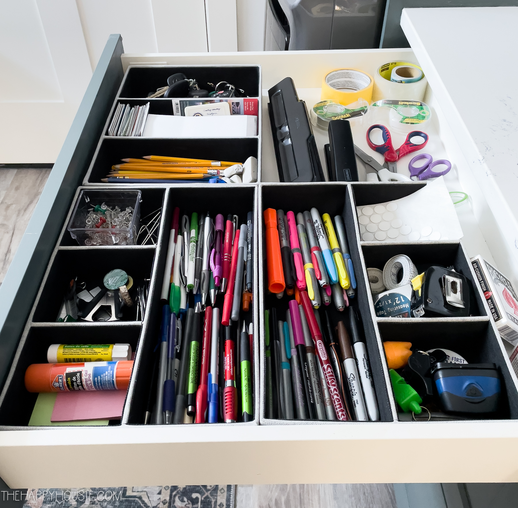 a junk drawer organized with drawer organizers to house home office supplies