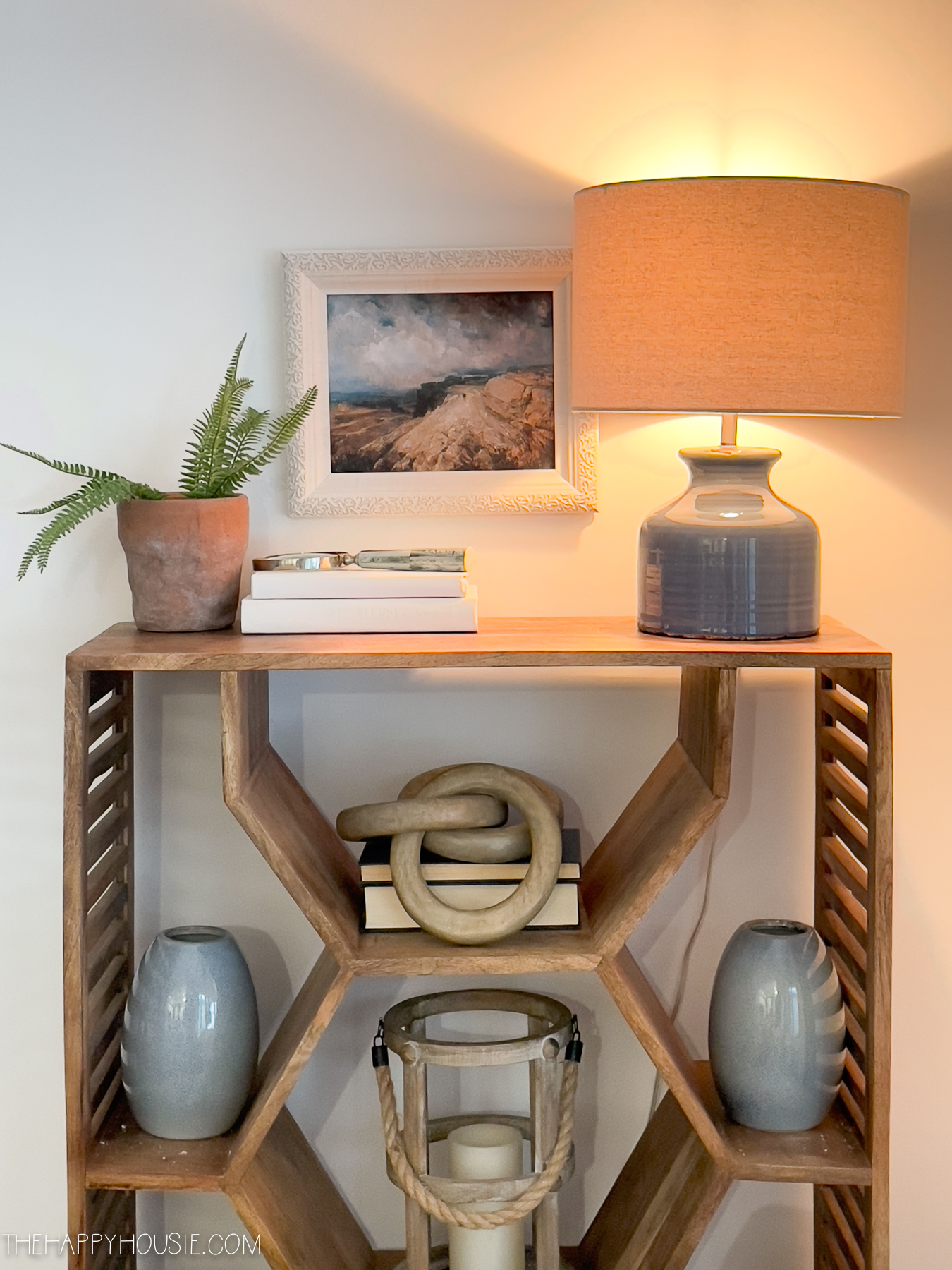 A wooden shelving unit with a lamp on top.