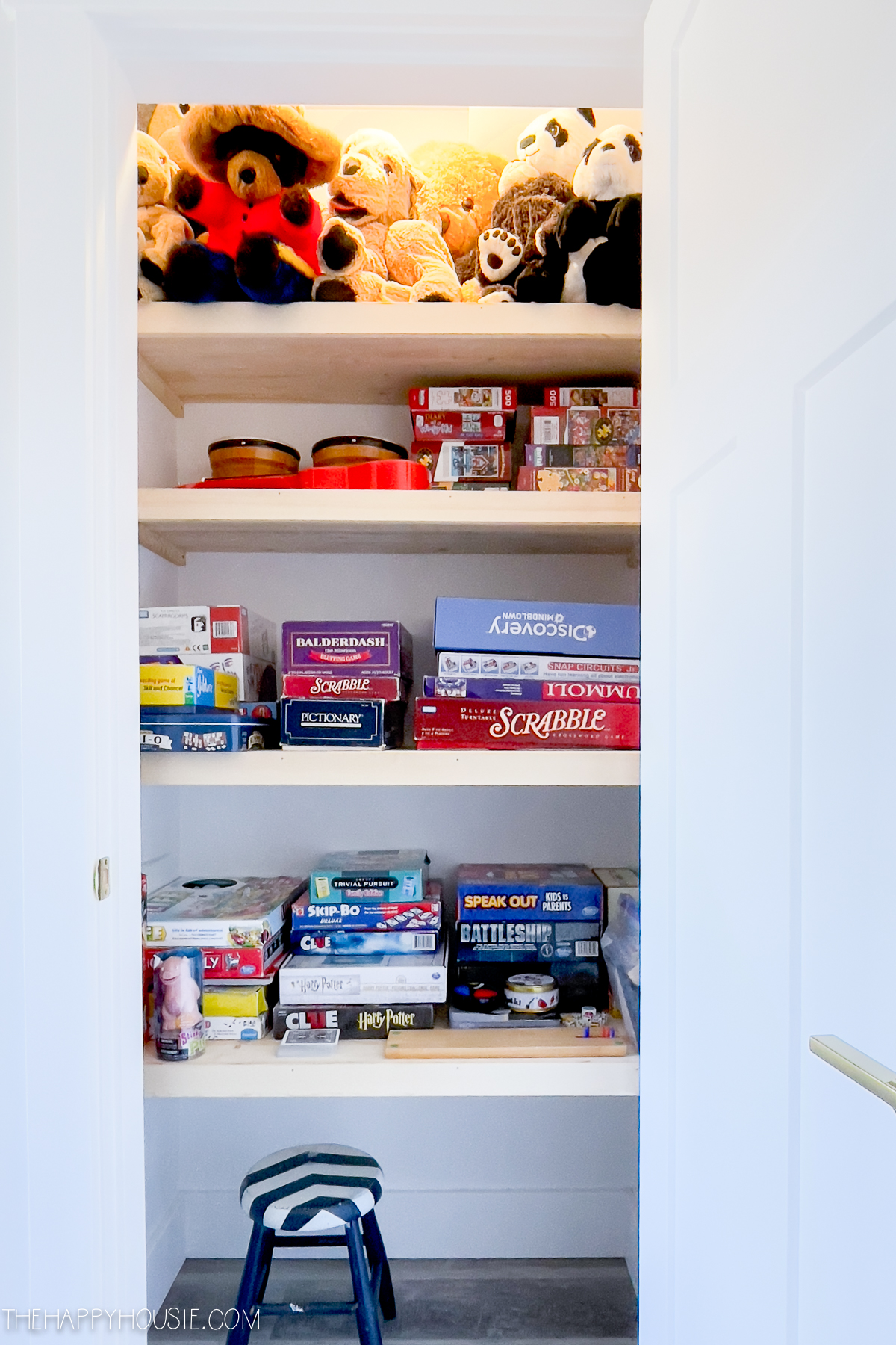 closet with wooden shelves used for playroom organization and storage of stuffies, games, and puzzles