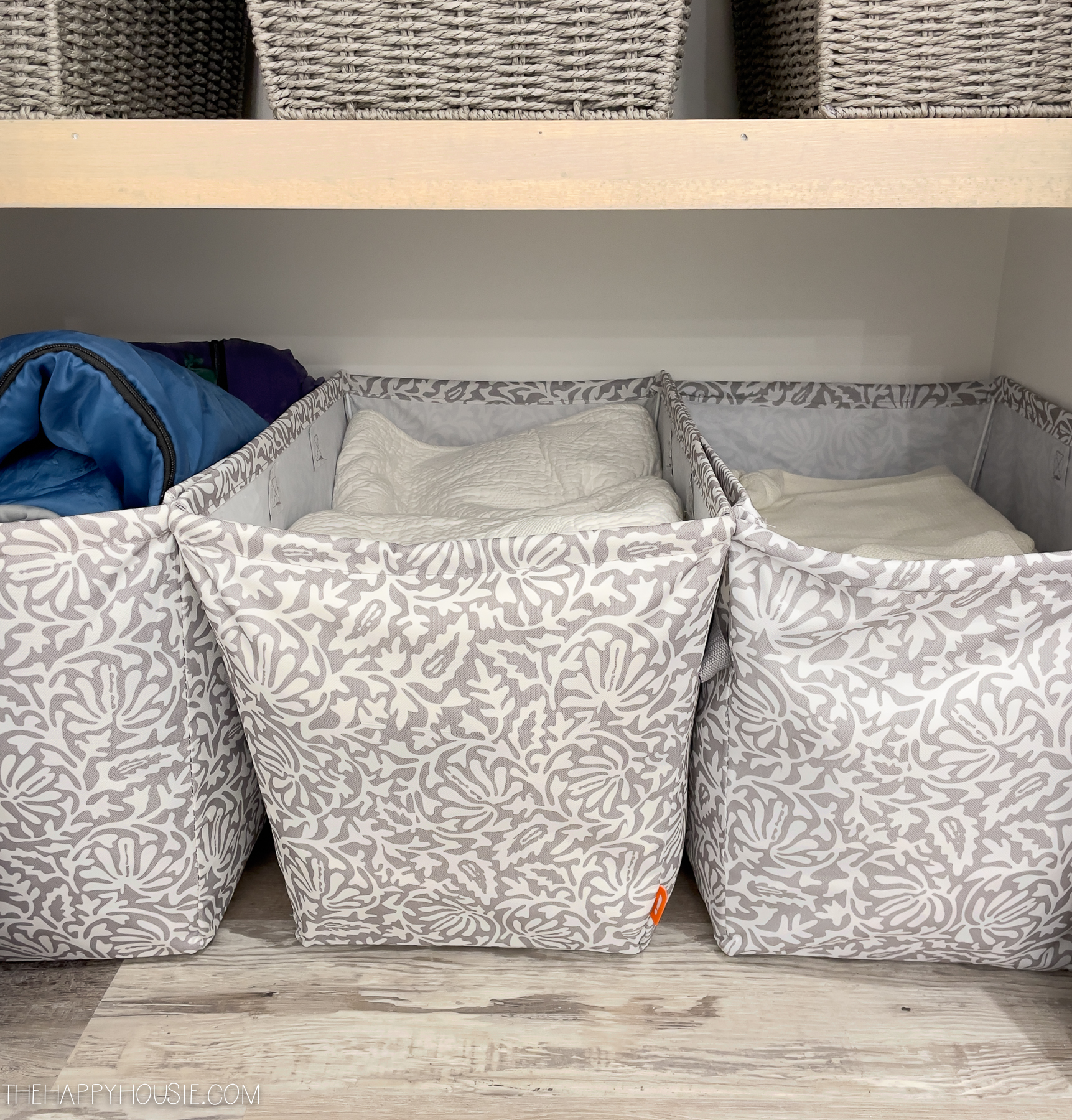 Cloth baskets with linen inside on the shelves.