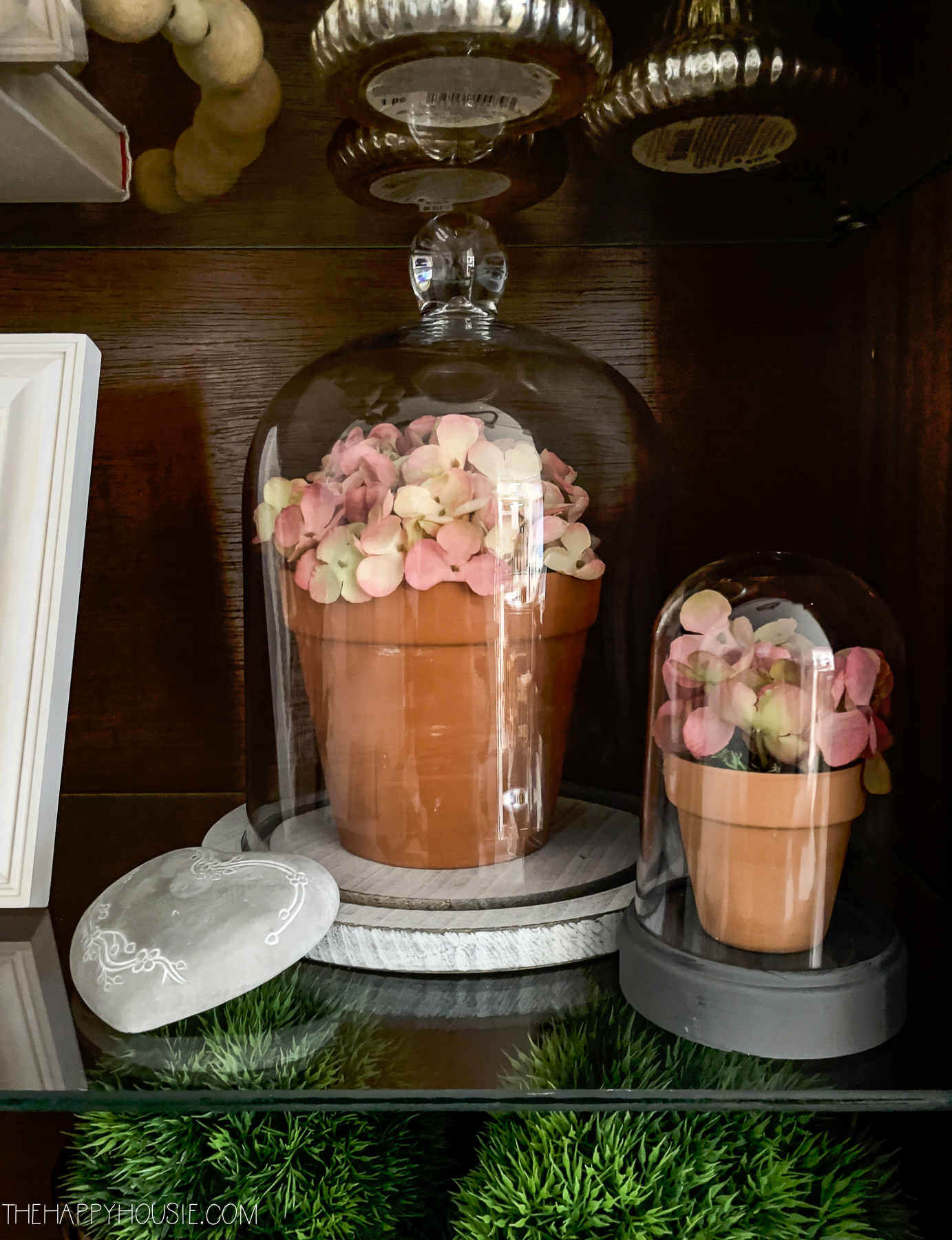Glass cloche with pink flower pots inside them.