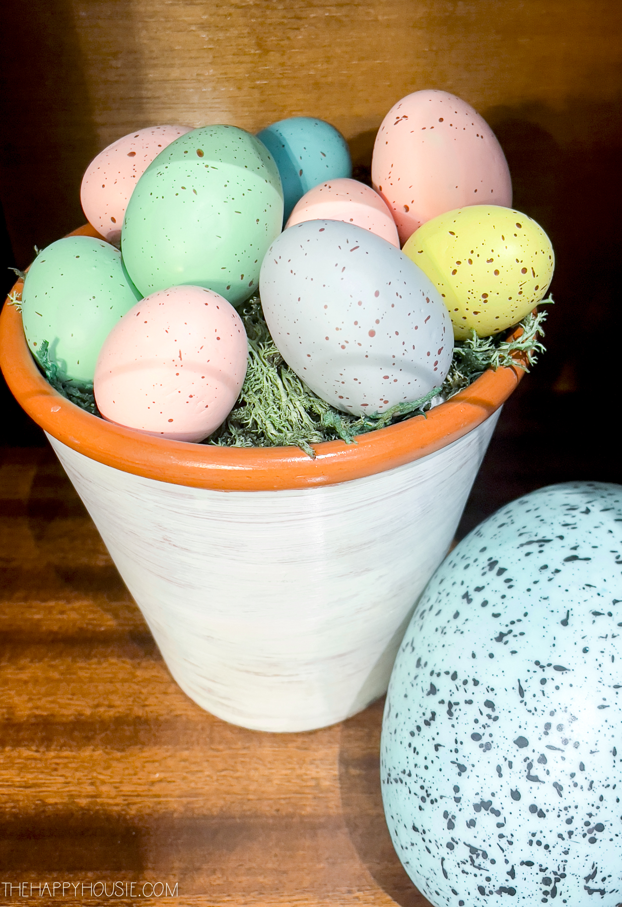 DIY speckled Easter eggs sitting on a bed of moss in a painted clay pot