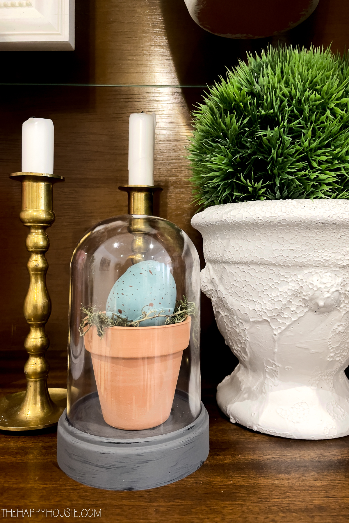 faux decorated Easter egg on a bed of moss in a tiny pot in a little cloche