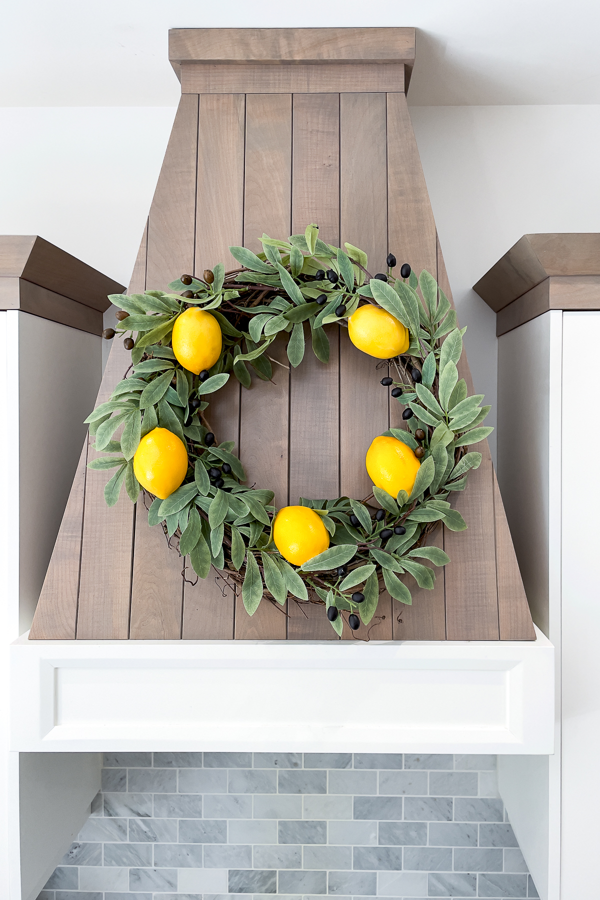 an olive branch and lemon spring kitchen wreath displayed in a kitchen