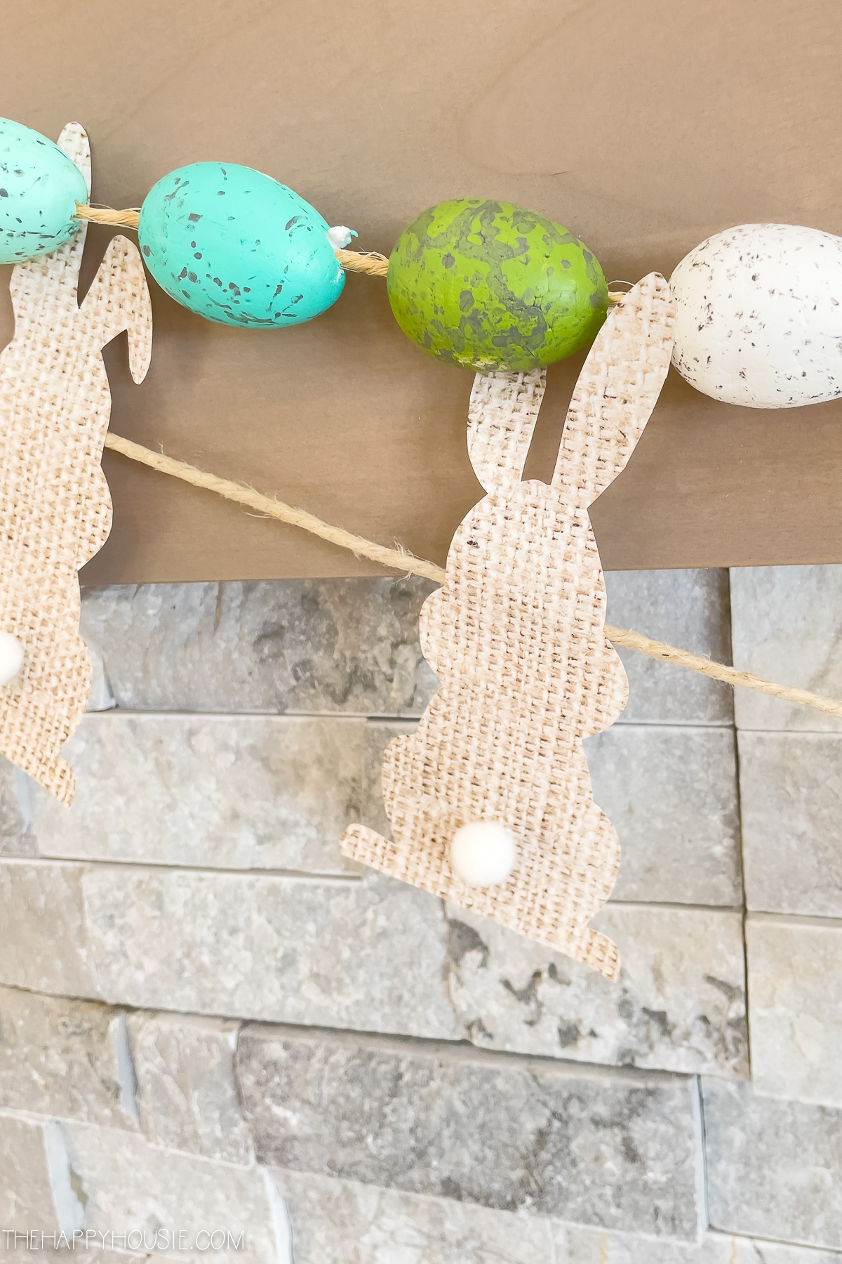 printed paper faux burlap Easter bunny with pompom tail hanging on an Easter banner