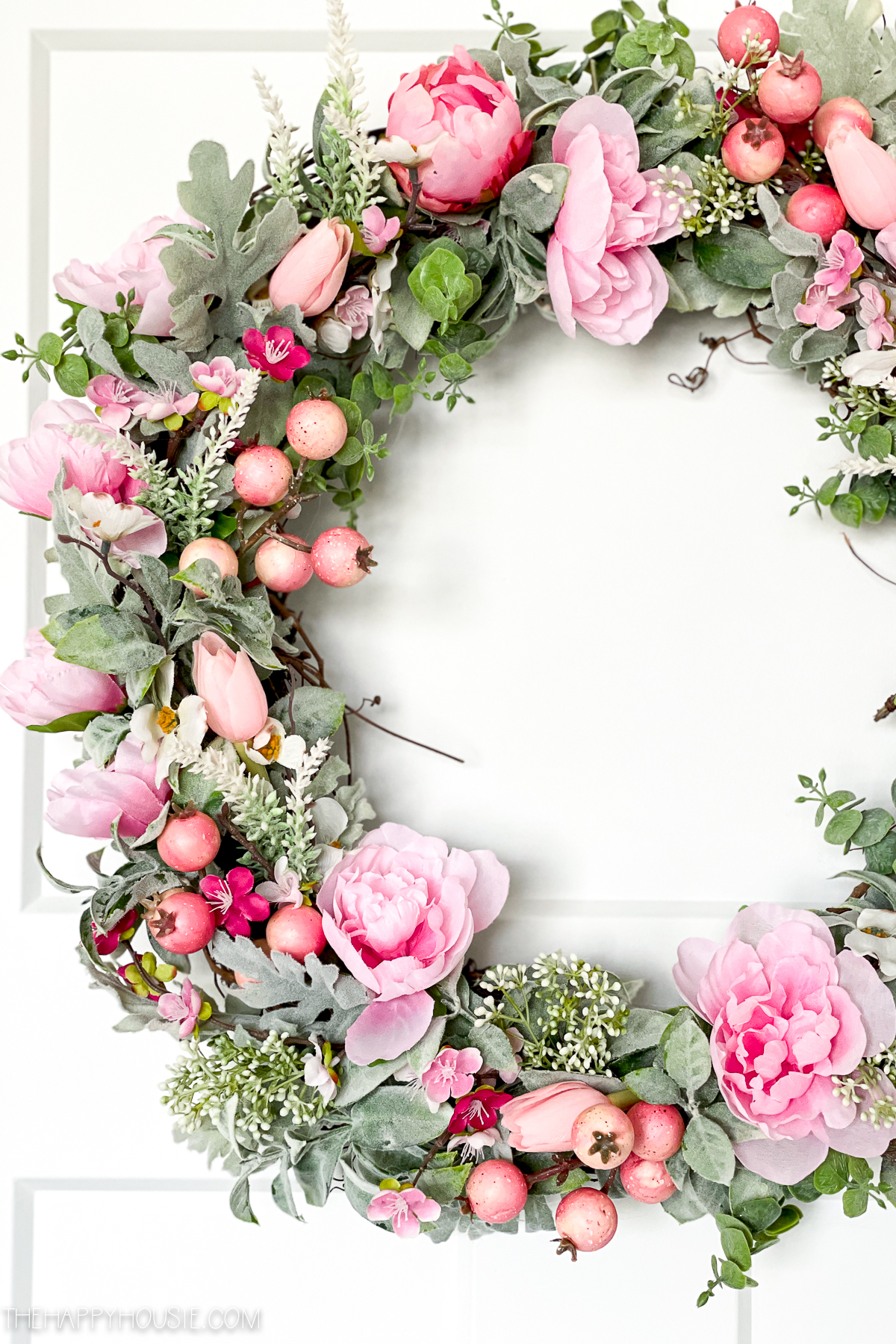 a DIY spring wreath made with faux greenery and pink blooms and berries