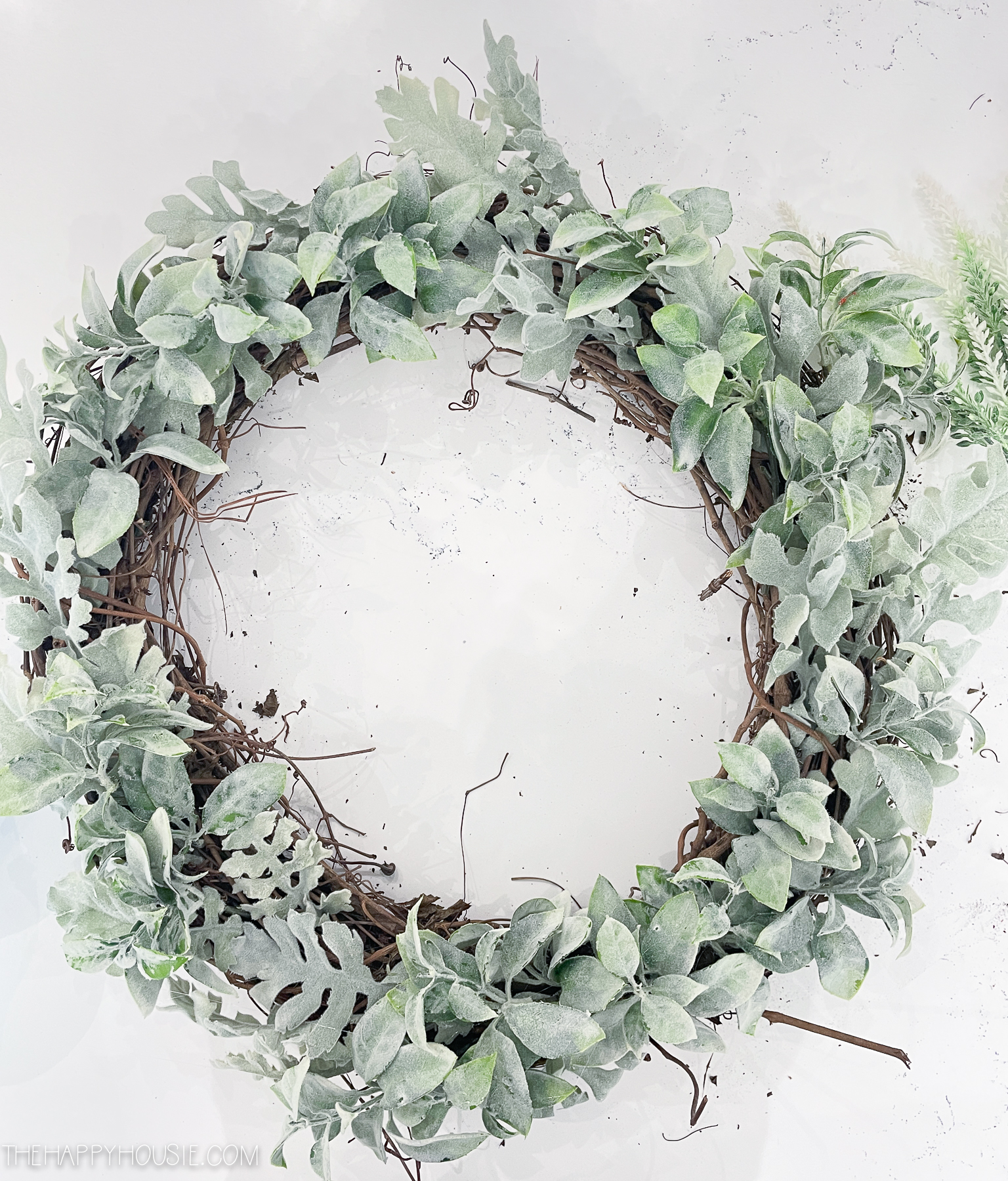 a grapevine wreath form stuffed with two types of faux greenery branches