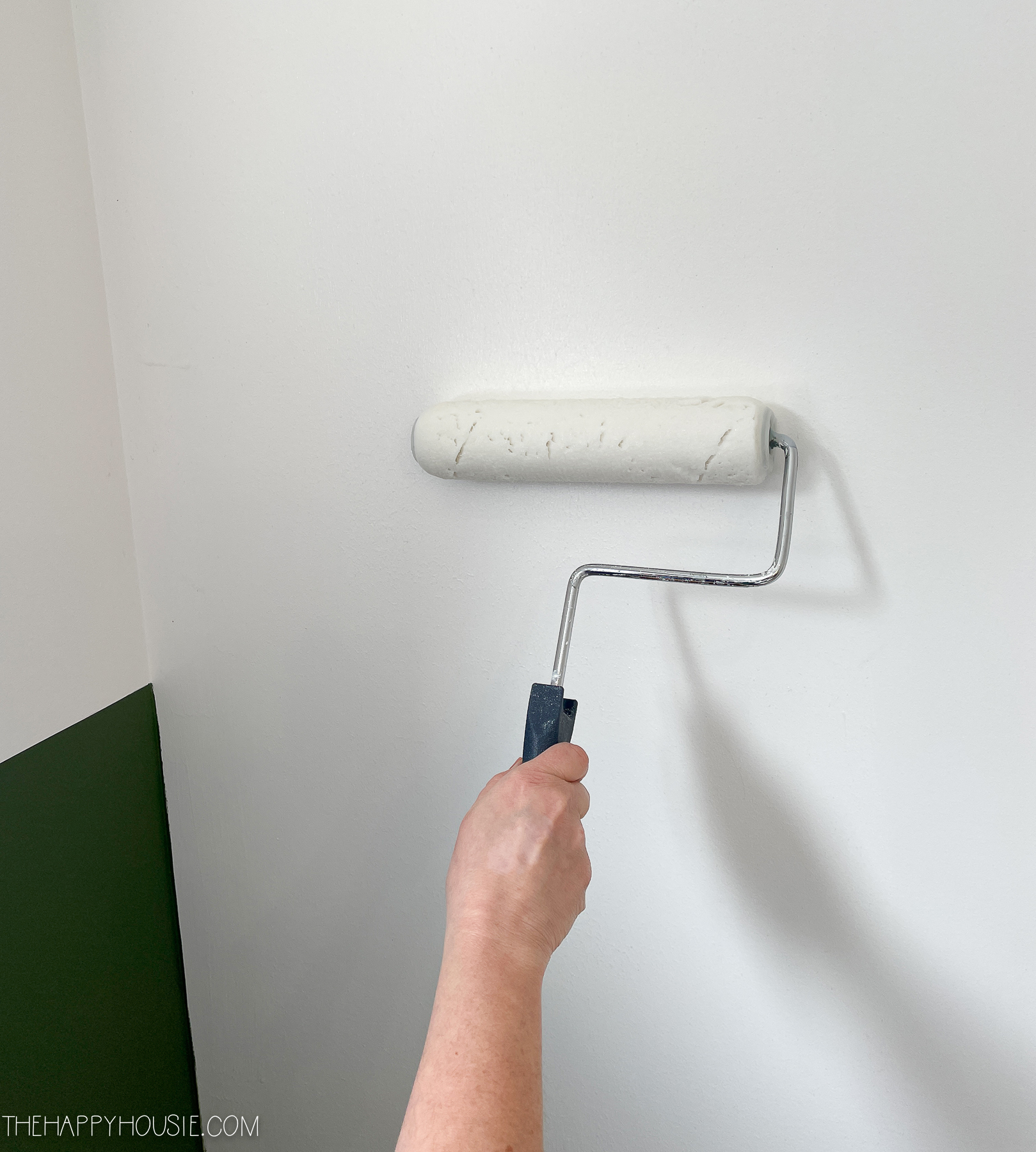 applying wallpaper paste to the wall using a roller