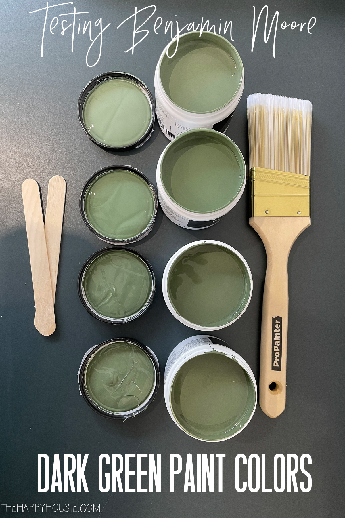 four sample paint pots with Benjamin Moore dark green paint colors in them 