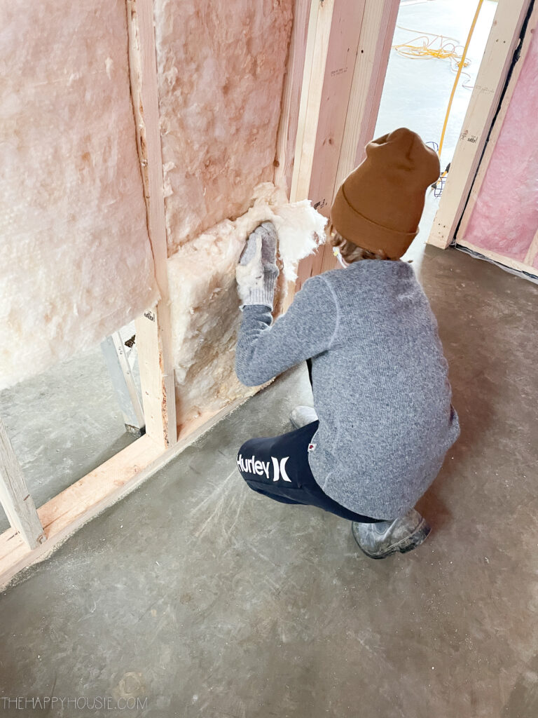 boy helping add insulation to interior walls in new build lake cabin