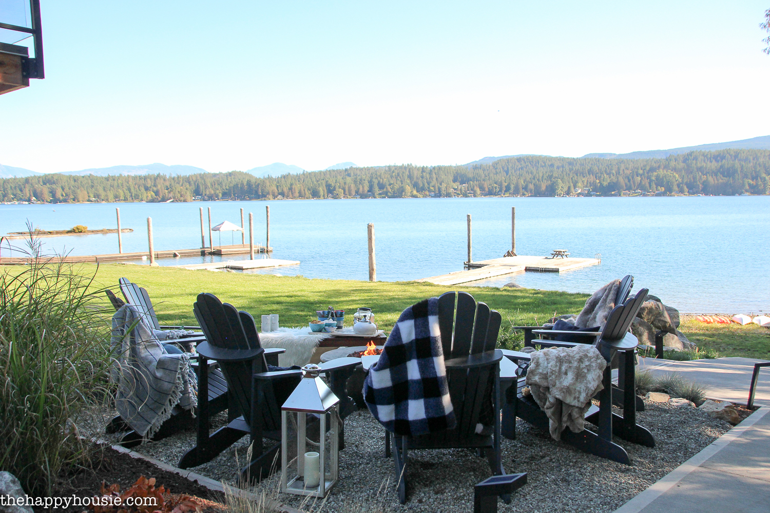 Adirondack chairs on a pea gravel patio with a lake view
