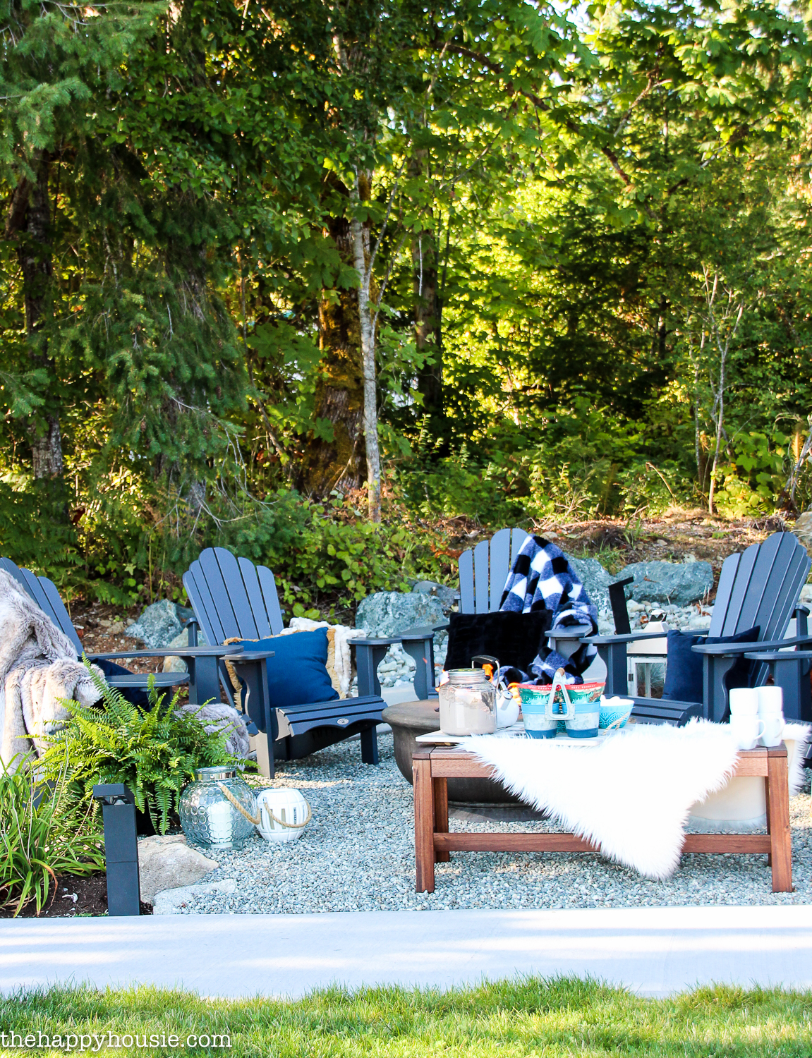 a pea gravel patio area with adirondack chairs backing against a forest
